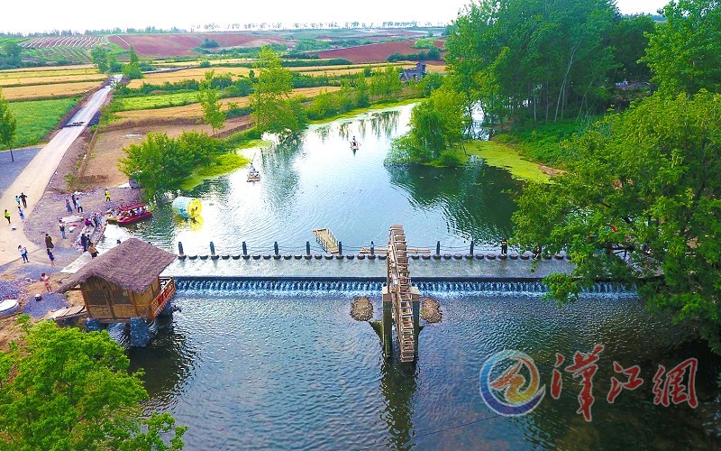 5月13日，游客在宜城市流水镇莺河村地边村头的小河里撑竹筏，游览小村风